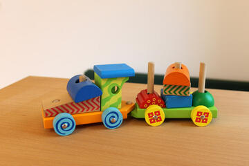 Eine bunte kleine Holzeisenbahn mit mit einem Waggon. Die kleine Eisenbahn kann auch auseinander und wieder zusammen gepuzzelt werden.