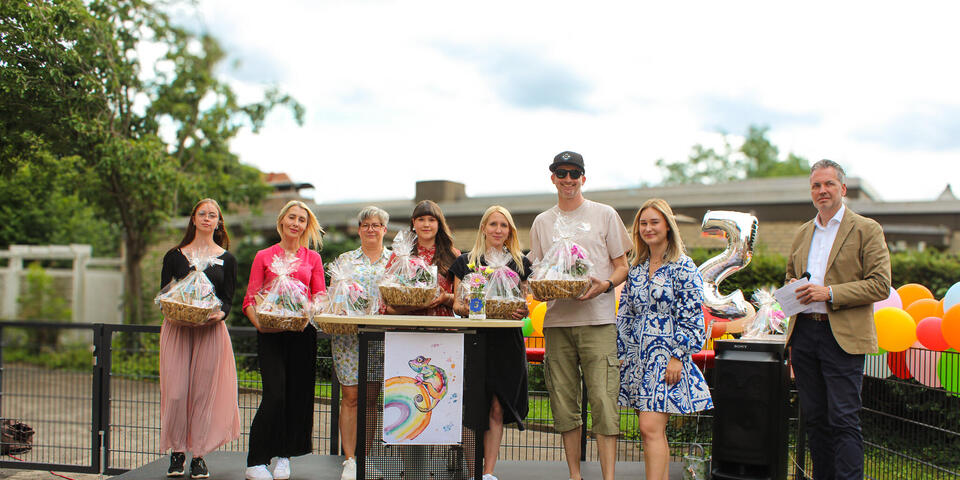 Eine Gruppe von Menschen auf einer Bühne. Manche halten einen Geschenkkorb