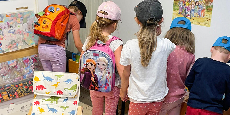 Kinder stöbern in einer Bücherei in Kästen mit Büchern