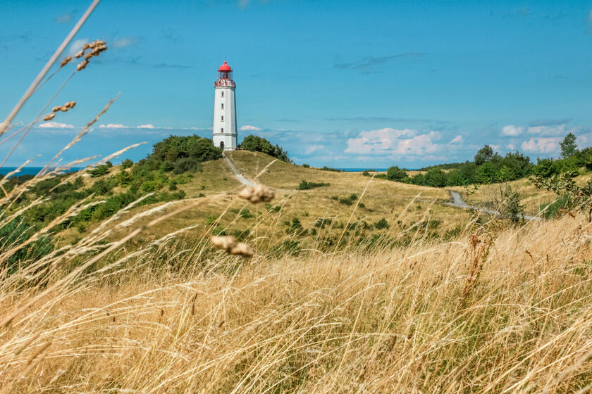 eine Dünenlandschaft mit einem Leuchtturn am Horizont