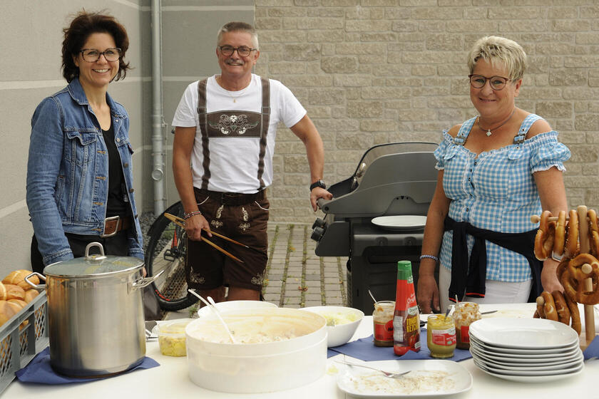 Ein Mann und eine Frau in bayrischer Tracht mit einer anderen Frau am Buffet