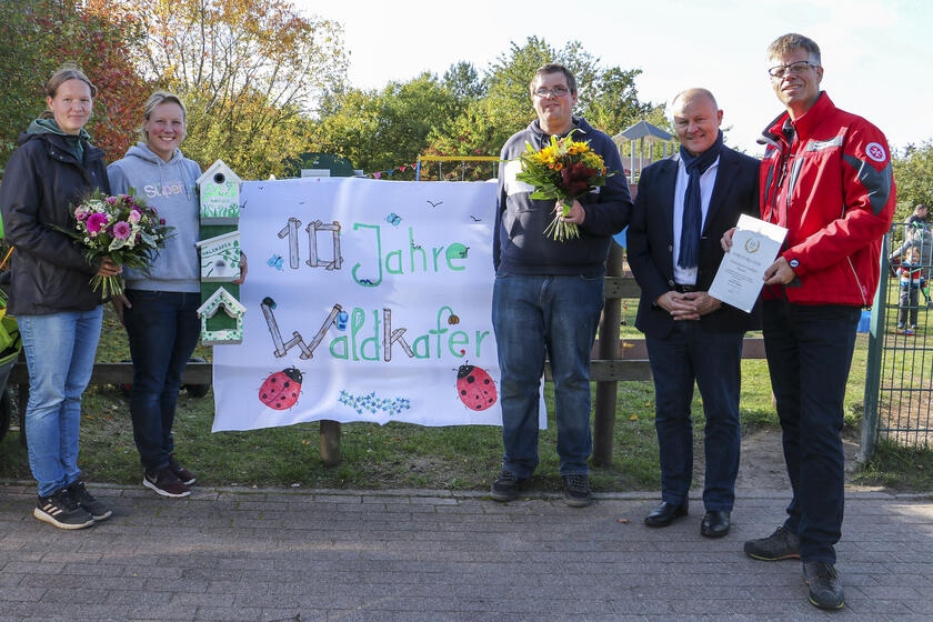 Nadja Schubring, Nicole Thele, Tobias Pieberg, Bürgermeister Jürgen Lamp und Johanniter-Bereichsleiter Peter Küpper (v.l.) feiern gemeinsam mit Team, Kindern und Eltern das zehnjährige Bestehen der Waldkäfer.
