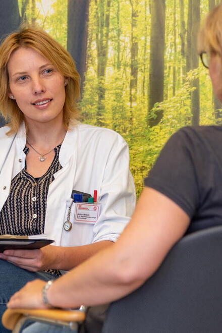 Ärztin bei einem Gespräch mit einer Patienten vor einer Waldtapete