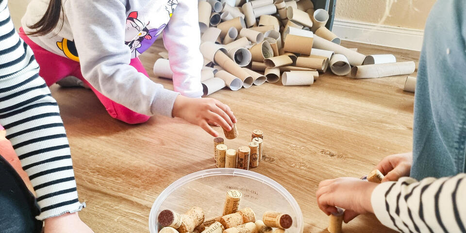 Kinderhände spielen mit Korken, die in einem Plastikeimer liegen