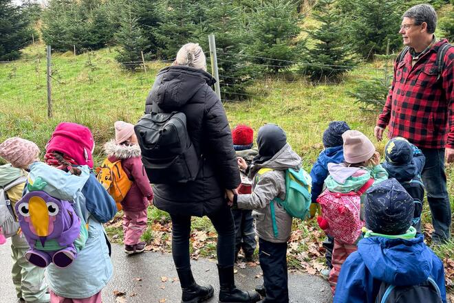 Eine Frau, ein Mann und eine Schar von Kindern schauen auf einen Wald.