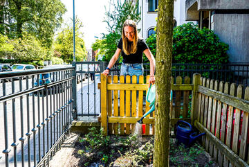 Erzieherin gießt die Pflanzen im Vorgarten der Krippe