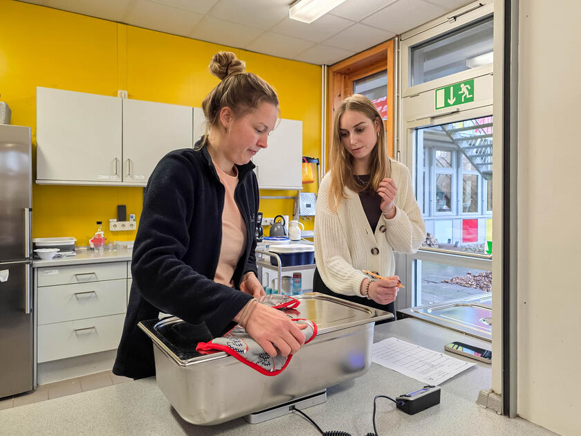Zwei Studentinnen wiegen einen Container mit Essen und dokumentieren das Gewicht.