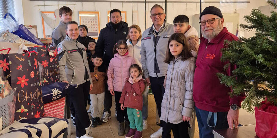 Eine Gruppe an Menschen mit Kindern stehen zusammen an den Rändern sieht man die Geschenke, die sie übergeben bekommen haben.