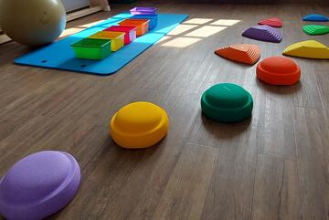 eine Turnmatte, ein großer Sitzball sowie bunte Balancier-Elemente im Bewegungsraum