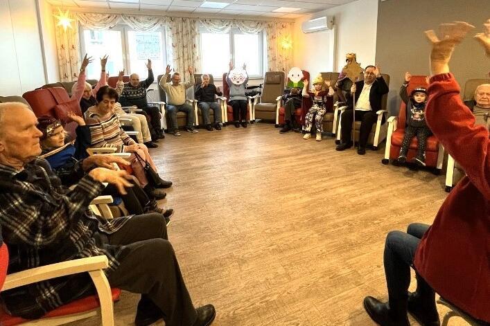 Tagespflegegäste und Sternsinger in großer Runde im Bewegungsraum