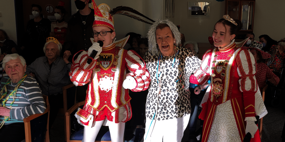 Eine kostümierte Seniorin steht zwischen dem Kinderprinzenpaar.