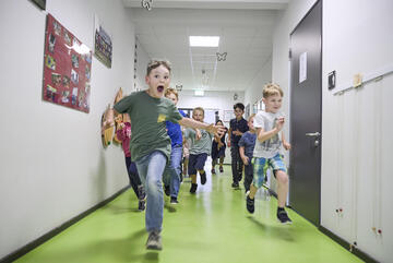 Kinder laufen einen Flur herunter.