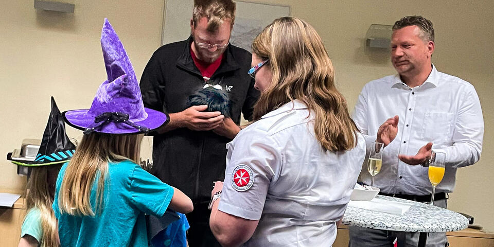Zwei Kinder und eine Frau überreichen einem mann ein Stofftier