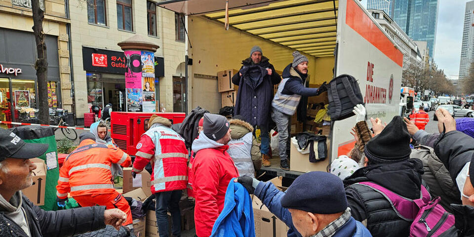 Aus der Ladewand eines LKWs werden warme Kleider an Bedürftige verteilt. 