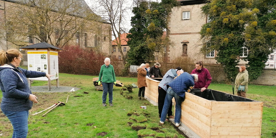 Menschen bauen Hochbeete in einem Park zusammen