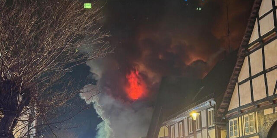 Einsatzkräfte vor einem brennendem Haus