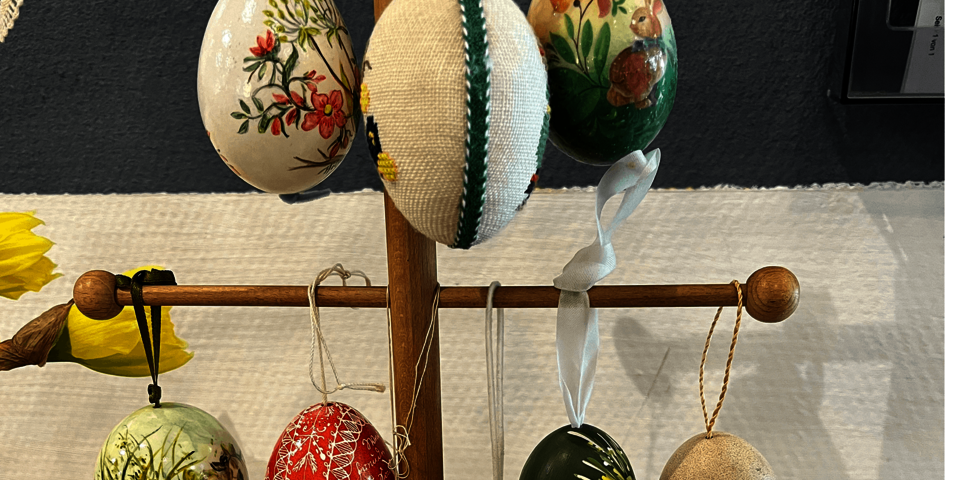 An einem Holzgestell hängen verzierte Eier.