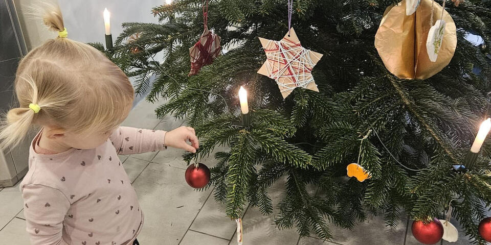 Ein kleines Mädchen schmückt einen Weihnachtsbaum