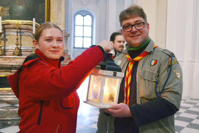 Ein Mädchen der Johanniter Jugend und ein Junge der Pfadfinder halten gemeinsam eine Laterne mit dem Friedenslicht darin in der Hand