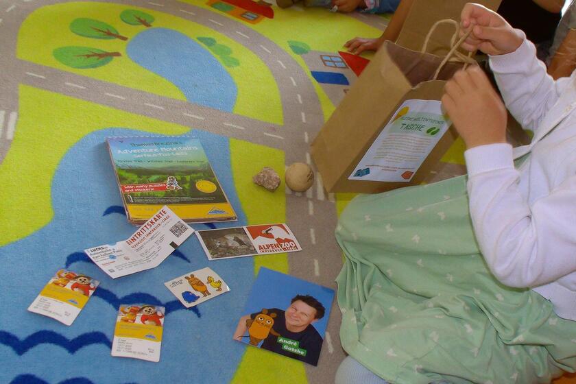 Kita-Kind leer Weltentdecker-Tüte und zeigt die Urlaubserinnerungen