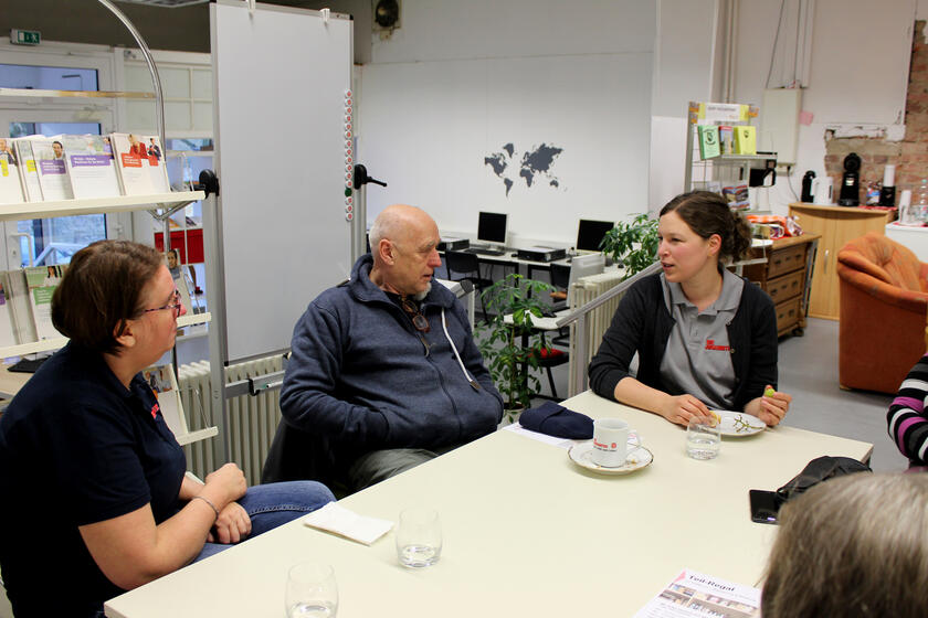 Personen sitzen gemütlich um einen Tisch und trinken Kaffee