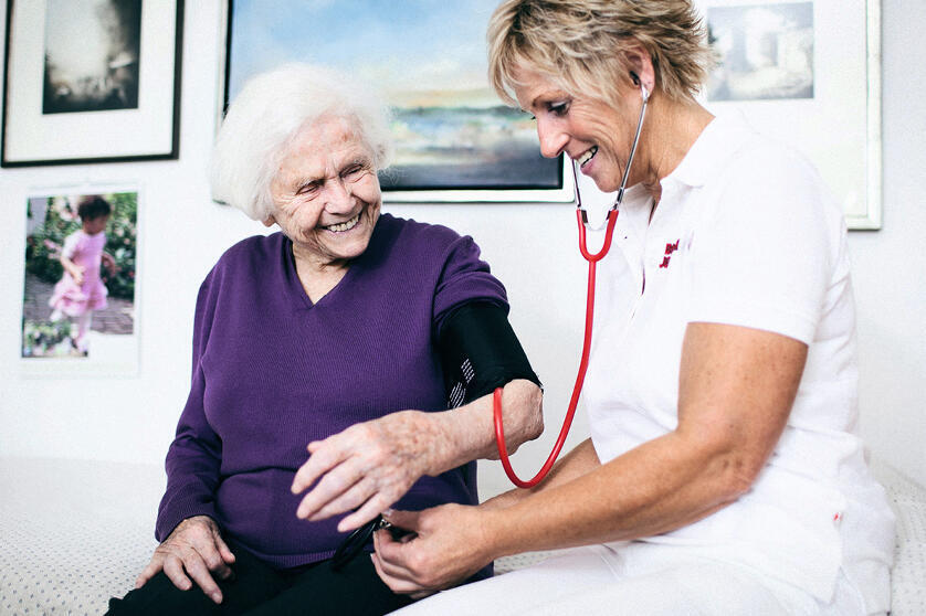 Eine Pflegerin der Johanniter misst den Puls einer älteren Frau.