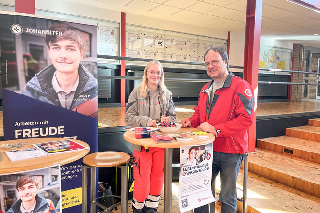 Eine junge Frau und ein Mann in Johanniter-Kleidung an einem Messestand