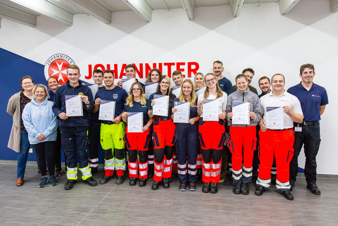Eine Gruppe von Menschen in Einsatzbekleidung mit Zertifikaten in den Händen