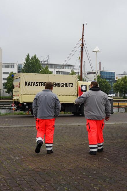 Man sieht zwei Personen vor einem LKW, auf dem "Katastrophenschutz" steht