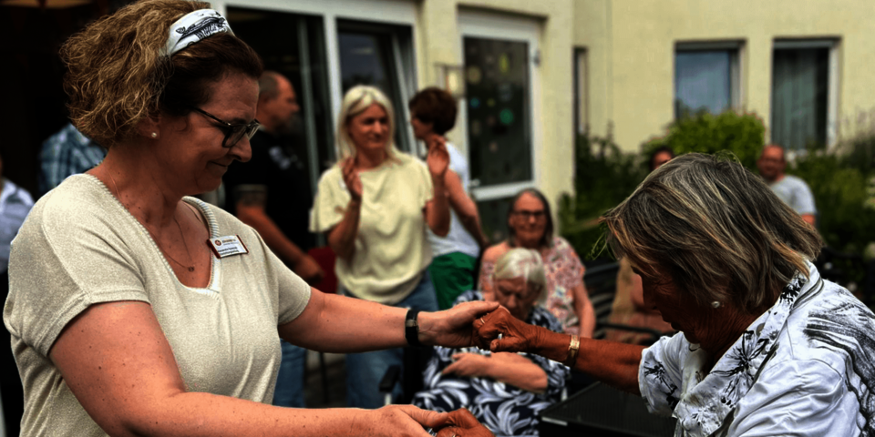 Zwei Frauen, eine jünger, eine älter, halten sich tanzend an den Händen.