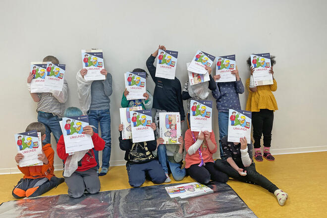Kinder halten Urkunden vor ihren Gesichtern