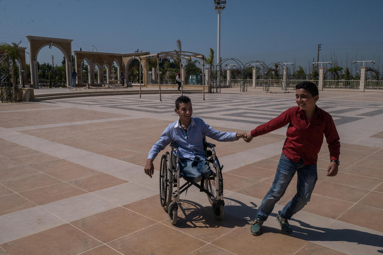 Ein Junge spielt mit einem anderen Jungen der im Rollstuhl sitzt