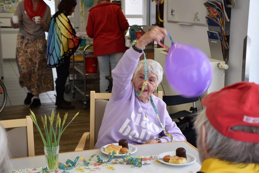 Eine Seniorin hält einen lila Luftballon in der Hand