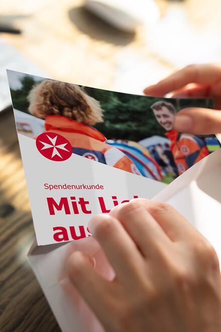 Zwei Hände ziehen eine Gutscheinkarte aus einem Briefumschlag