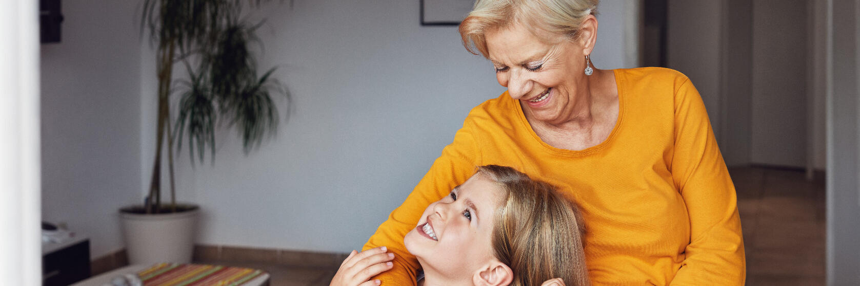 Eine Großmutter mit ihrer Enkelin. Die Oma trägt einen Hausnotruf-Sender am Handgelenk.