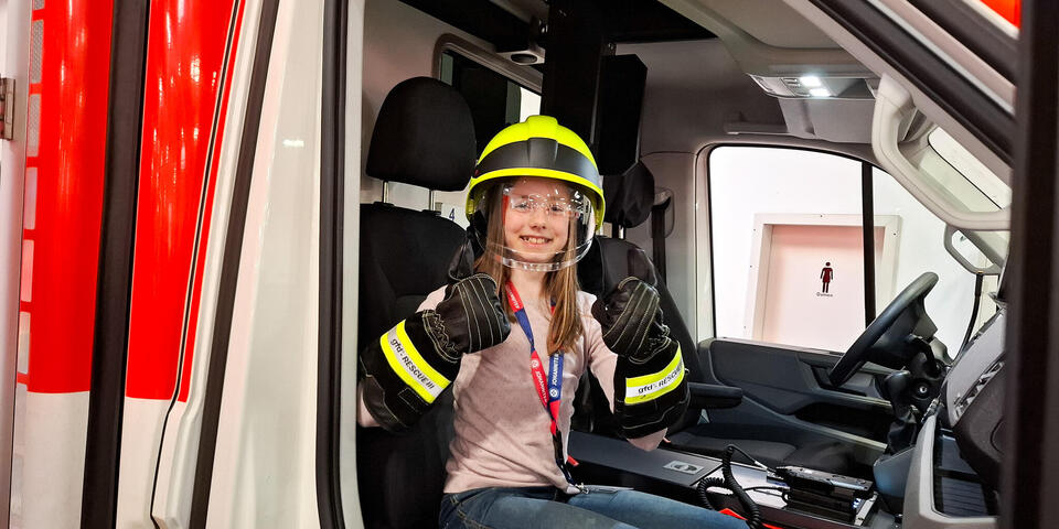 Ein Mädchen mit Einsatzhelm in einem RTW