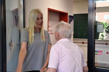 die Leitung der Tagespflegeeinrichtung begrüßt eine Dame, die zur Tür hereinkommt