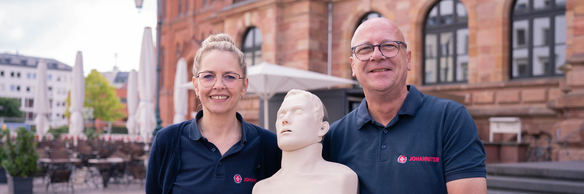 Zwei Erste-Hilfe-Trainees halten eine Reanimationspuppe.