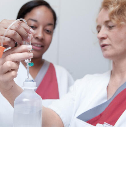 Zwei Frauen in weißen Kitteln bereiten eine Infusion vor.