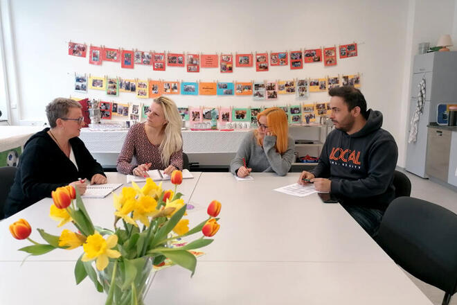 Mitarbeitende sitzen gemeinsam am Tisch und bereiten die anstehende Veranstaltung vor. 