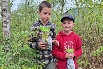 Zwei Jungen stehen zwischen Bäumen und tragen ihre Ostertüten.