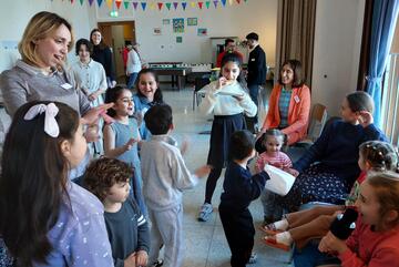 Eine Betreuerin mit einer Gruppe von Kindern; sie erklärt ihnen ein Spiel