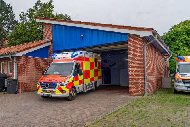 Ein Rettungswagen fährt mit Blaulicht aus der Fahrzeughalle der Rettungswache Cismar.