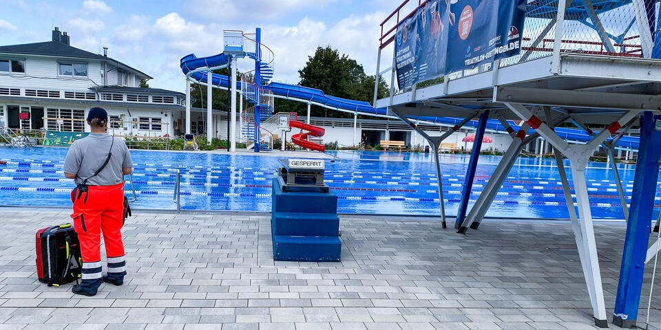 Ein Johanniter steht am Beckenrand eines großen Schwimmbades