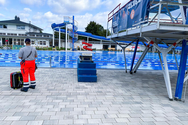 Ein Johanniter steht am Beckenrand eines großen Schwimmbades