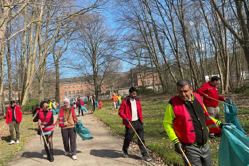 Bewohnende und Mitarbeitende der Landesunterkunft Kiel sammeln Müll in der Wik ein.