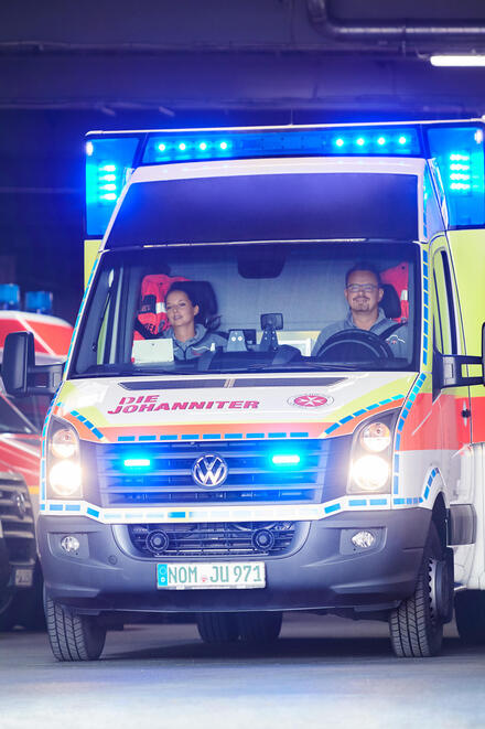 Ein Johanniter-Rettungswagen fährt mit Blaulicht aus der Fahrzeughalle.