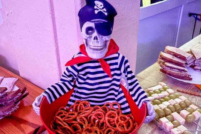Halloweenparty in der Kita Traumland Das Buffet bei der Halloween-Party in der Johanniter-Kita Traumland wurde von den Eltern der Kinder organisiert. Ein Figur (Skelett-Pirat) hält eine Schüssel mit Mini-Brezeln.
