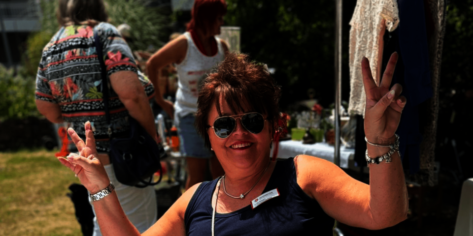 Eine Frau mit Sonnenbrille macht mit beiden Händen das "Victoryzeichen" (ein V mit zwei Fingern)