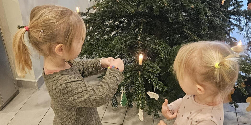 Zwei kleine Mädchen schmücken einen Weihnachtsbaum